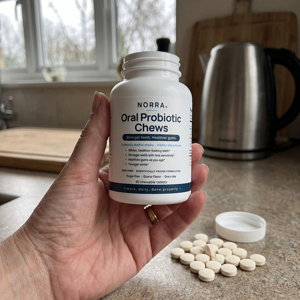 A hand holding an opened bottle of Norra with chews on the counter